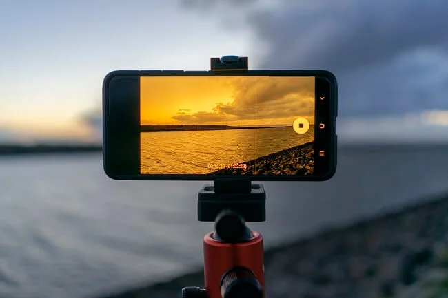 A mobile phone placed on a tripod on a beach in evening time clicking photo. - Copy
