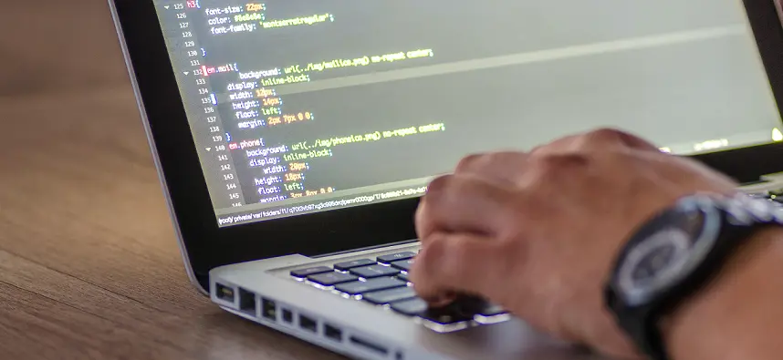 Website developer writing code on his laptop