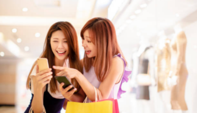 Two women in a shopping mall engrossed in their phones.