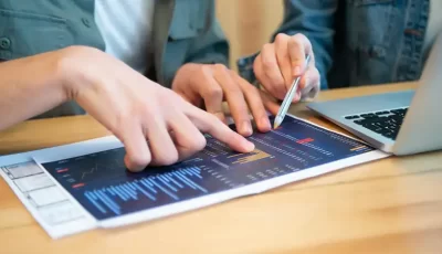 Two pair of hands working on a piece of paper with graphs on it