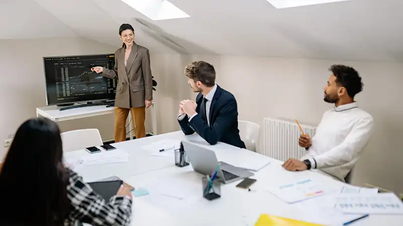 A woman giving a presentation to three people sitting in front of her