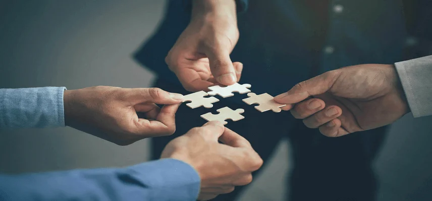 Four people trying to join their jigsaw puzzle piece