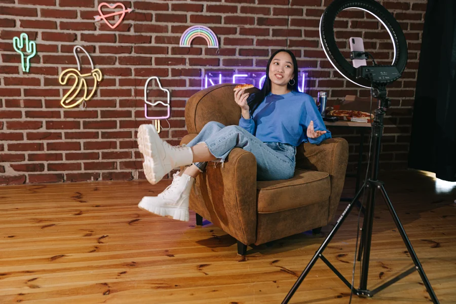 A lady sitting in a chair with a pizza in her hand and studio lights facing her