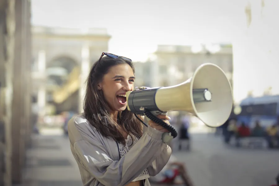 A lady holding a megaphone and saying something in it]