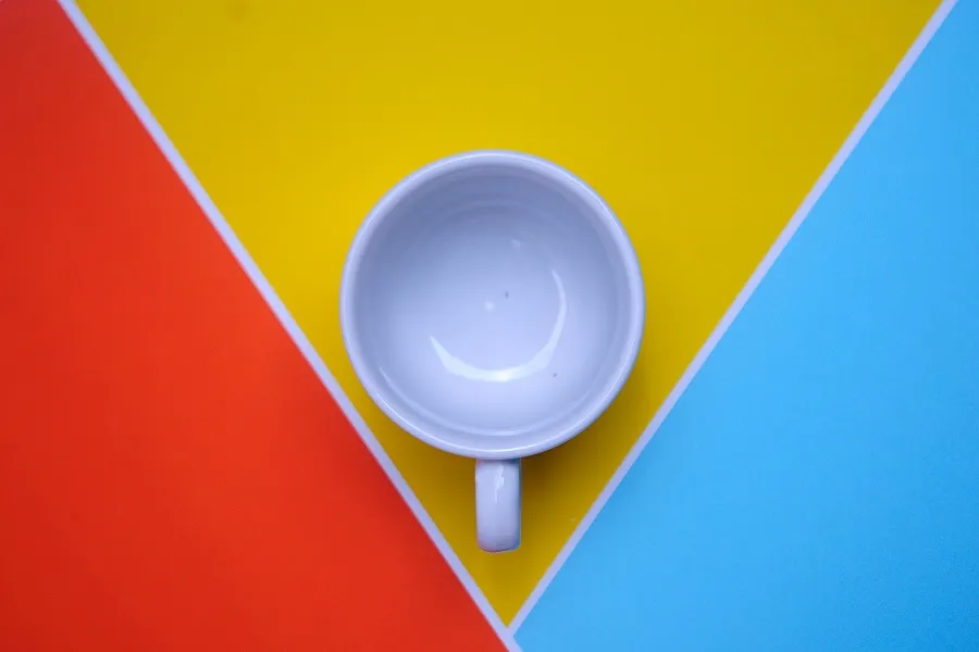 A mug placed on the yellow background with 2 different colored triangles