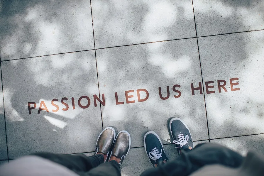 PASSION LED US HERE written on the footpath and two people standing near it